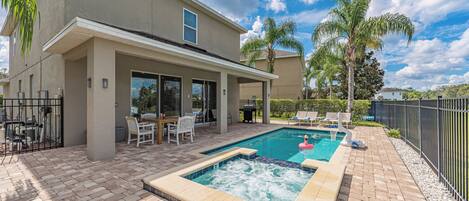 A two-story house with a swimming pool, patio furniture, and a view of the ocean.