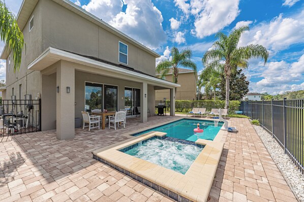 A two-story house with a swimming pool, patio furniture, and a view of the ocean. - Luxury 5BR Villa, Private Pool/Spa, 15 Min Disney! (Kissimmee)