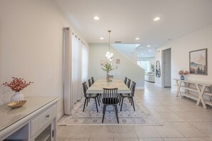 A modern dining area with a rectangular table, black chairs, and a decorative vase. - Luxury 5BR Villa, Private Pool/Spa, 15 Min Disney! (Kissimmee)