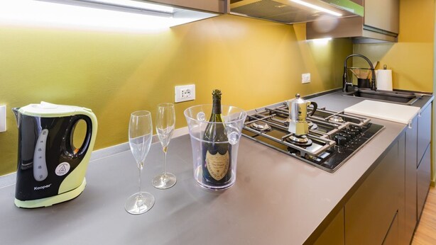 Una cocina moderna con una tetera, vasos y una botella de champán sobre la encimera.