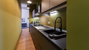 Una cocina moderna con encimera negra, pileta de acero inoxidable y estufa.
