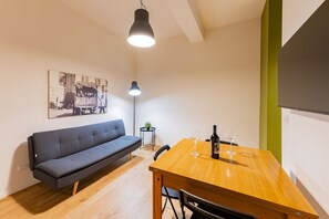 A modern room with a sofa, a wooden dining table, a small side table with a plant, and a wall-mounted picture. - GuestHost - Modern 60 sqm apartment, ideal for 4 people, located on the ground floor of a renovated single house WITHOUT a lift (one step to access it). The accommodation is located in Pescara Colli, in a quiet residential neighborhood, where you can enj (Pescara)