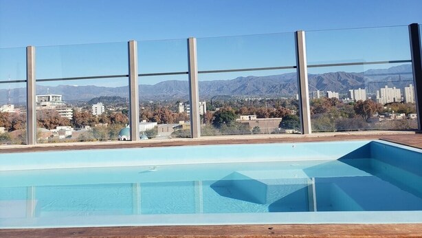 Ein Schwimmbecken mit freiem Blick auf Berge und Gebäude im Hintergrund.