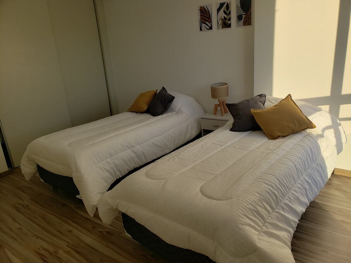A bedroom with two beds, a nightstand, and a lamp.