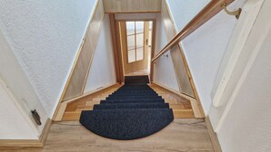 A wooden staircase with a dark carpet at the bottom, leading to a door with a window. - Weitsicht, Deutschland (Kühlungsborn)