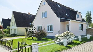 A two-story residential building with a sloped roof, a small porch, and a well-maintained lawn. - Weitsicht, Deutschland (Kühlungsborn)