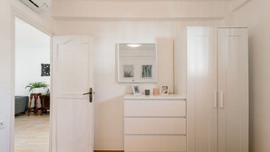 Een kamer met een witte kast, een spiegel en een klein tafeltje met een plant.