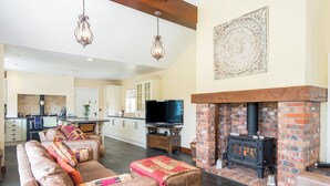 A spacious living room with a fireplace, a television, and a kitchen in the background. - 1 Homecroft Bungalows, Holiday Cottage Saundersfoot, Sleeps 6, 3 bedrooms,  bathrooms (Saundersfoot)