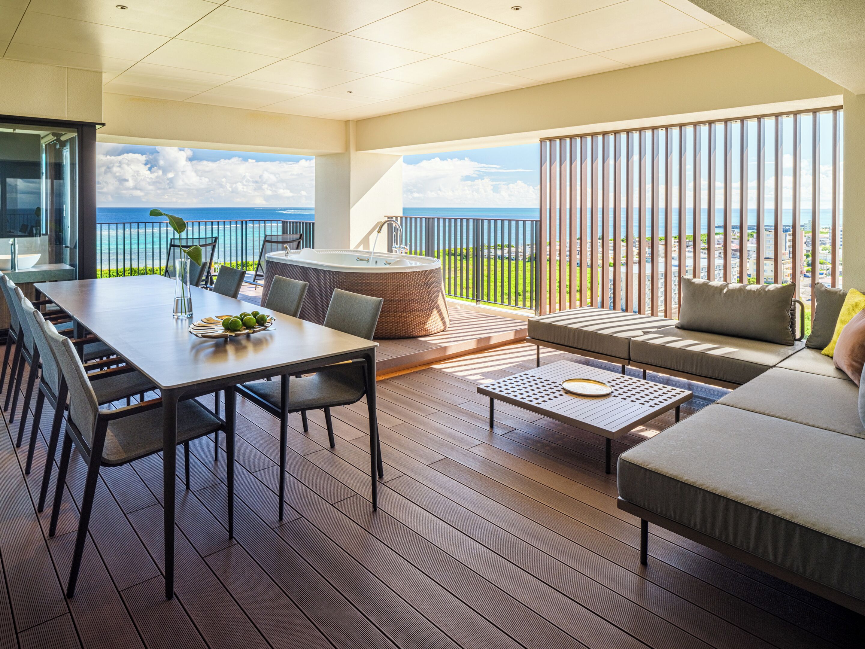 A spacious outdoor area with a dining table, chairs, a hot tub, and a sofa.
