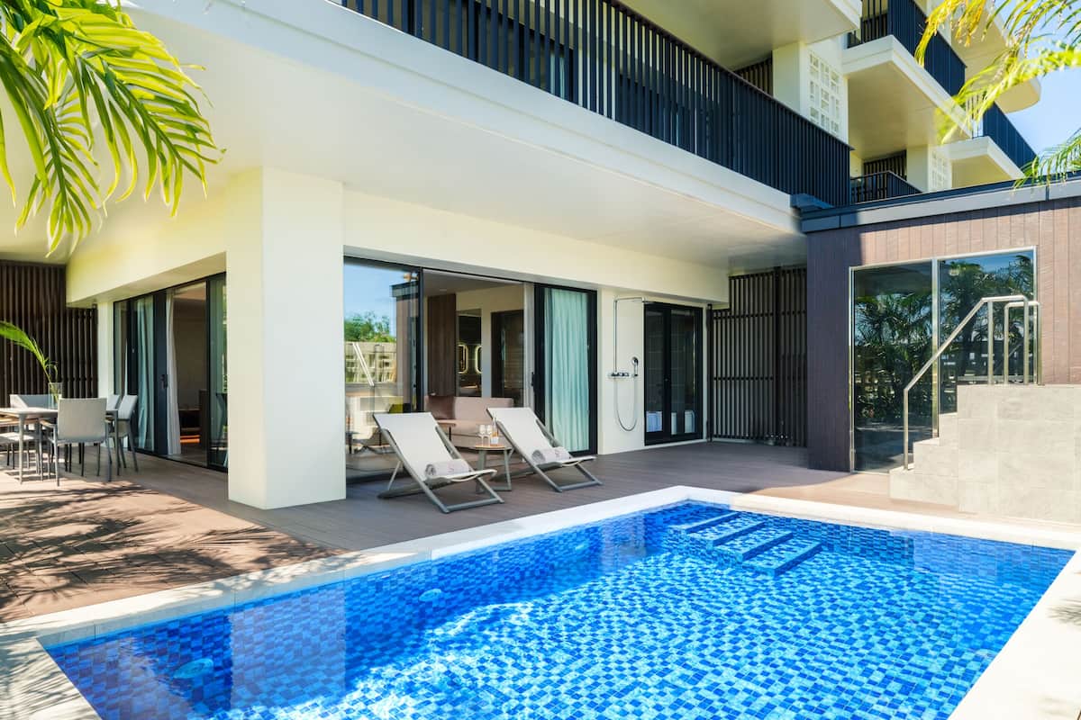 A modern pool area with lounge chairs and a glass-enclosed patio.