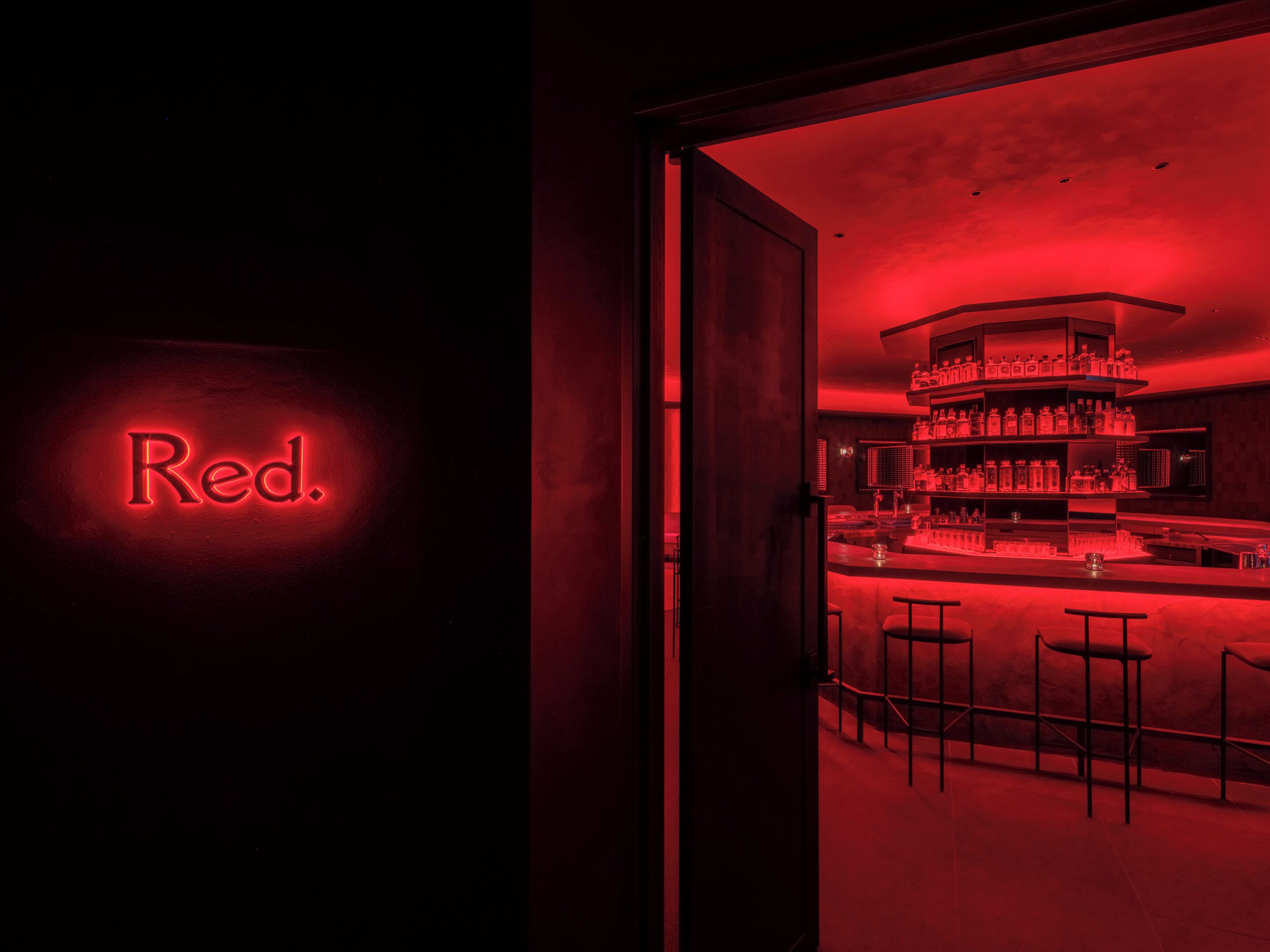 A bar area with a red neon sign reading "Red."