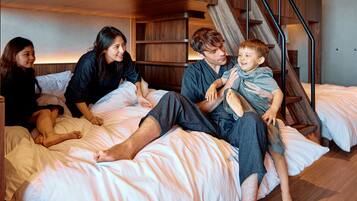 Une famille de quatre personnes partage un lit superposé avec un escalier en bois et des étagères intégrées.