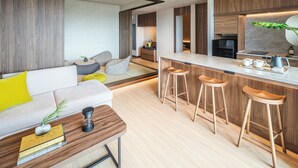 Une cuisine moderne avec des meubles en bois, un coin bar avec des tabourets et un espace détente avec un canapé et des coussins.