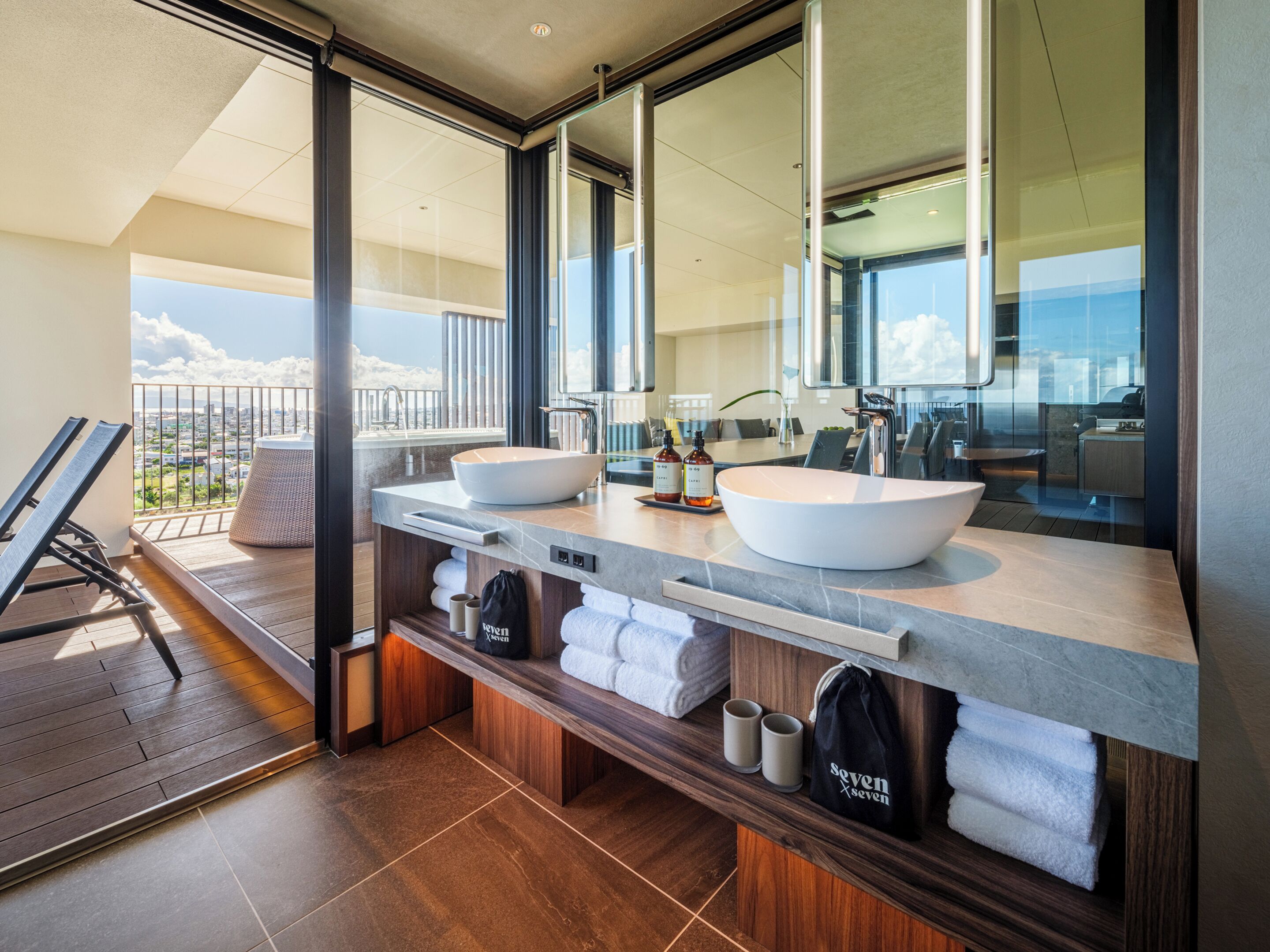 Une salle de bain moderne avec deux grands lavabos, un miroir et une vue sur la ville.