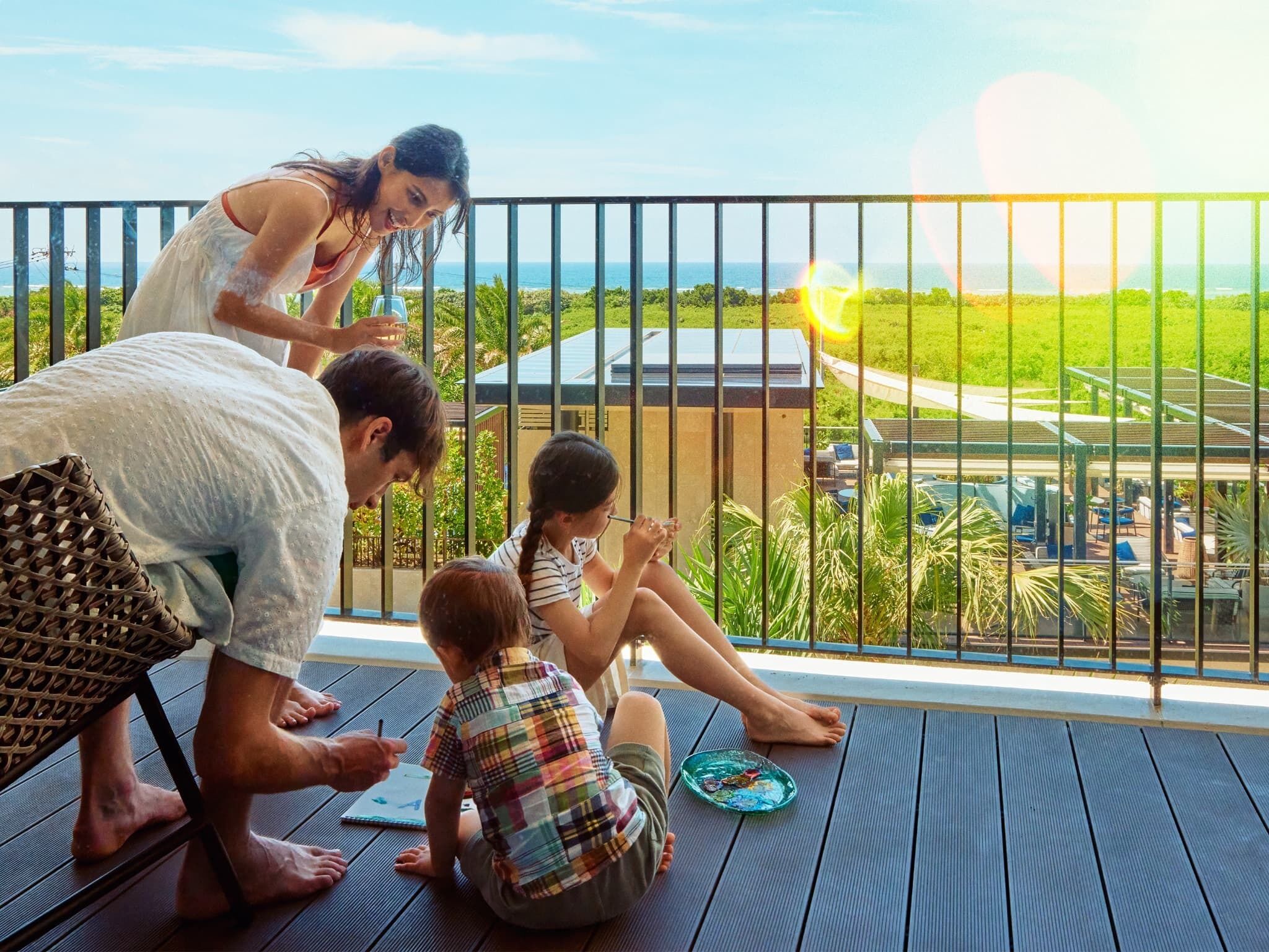 Une famille sur un balcon, avec vue sur une piscine et un espace verdoyant.