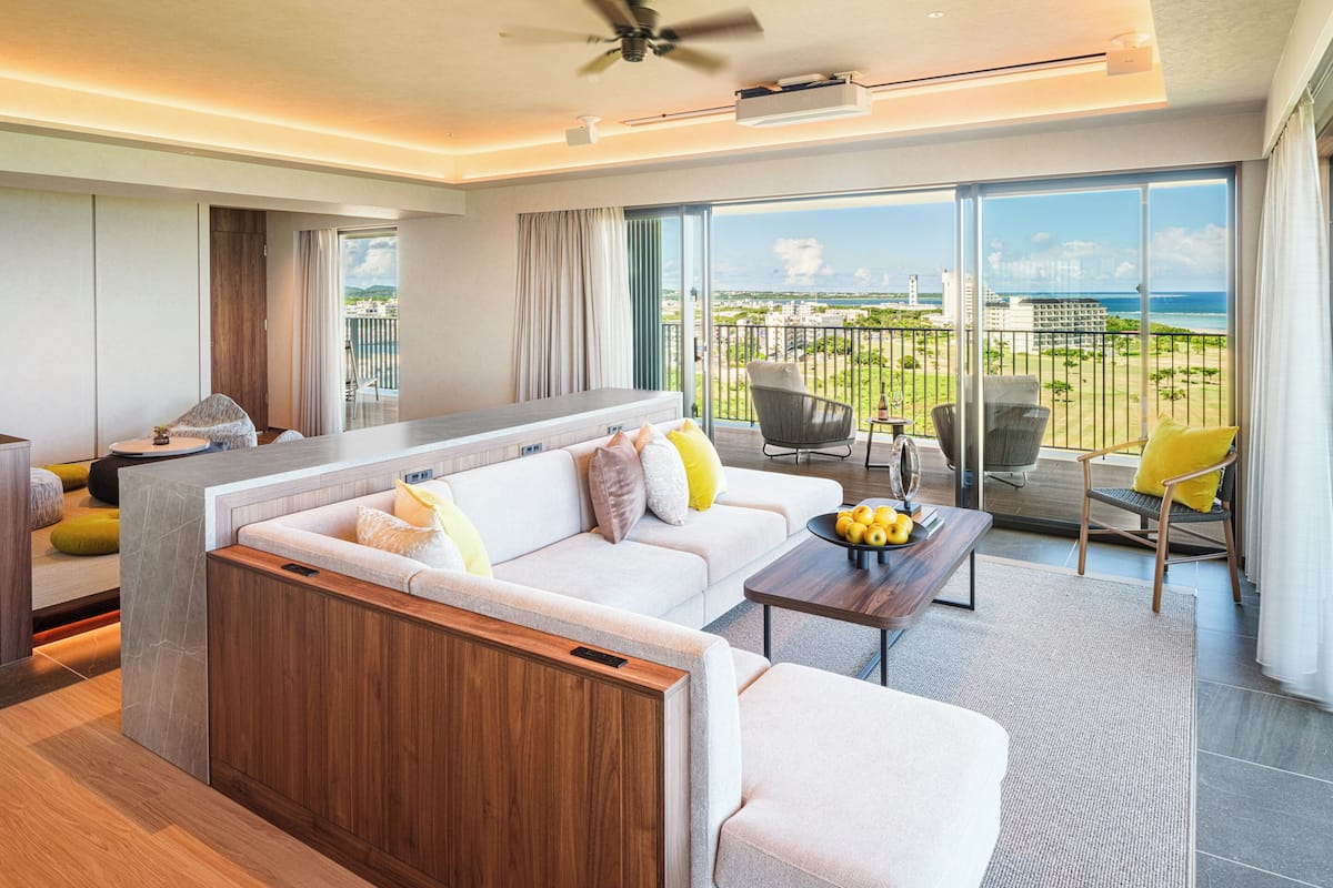 A modern living room with a sofa, chairs, a coffee table, and a view of the ocean.