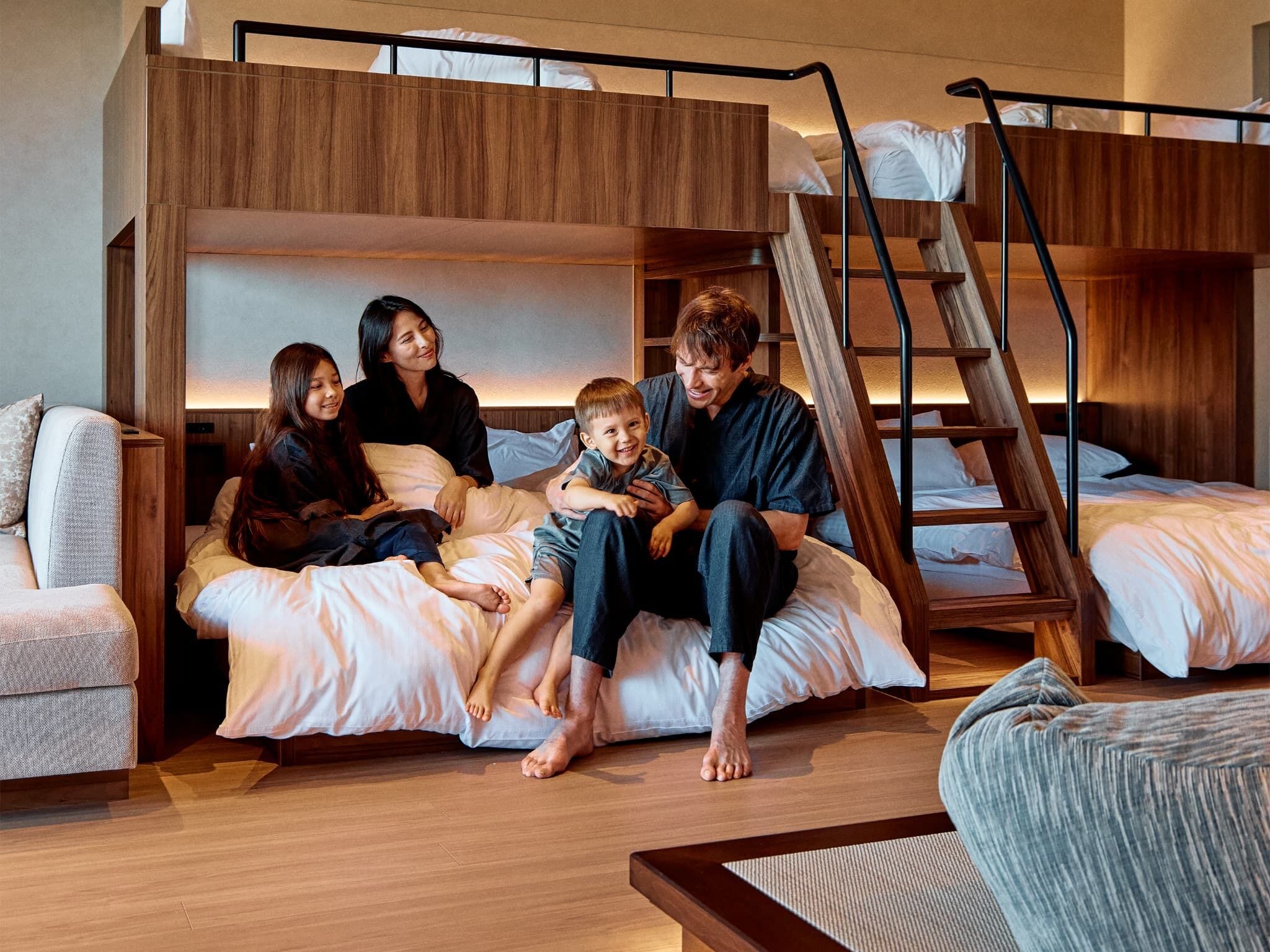 Een slaapkamer met een stapelbed, een houten ladder, een bank en een salontafel.