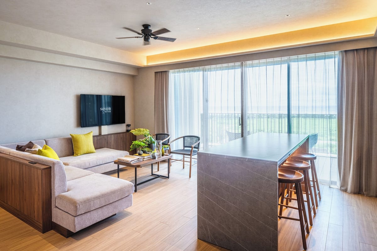 A modern living room with a sofa, coffee table, and a bar area with stools.