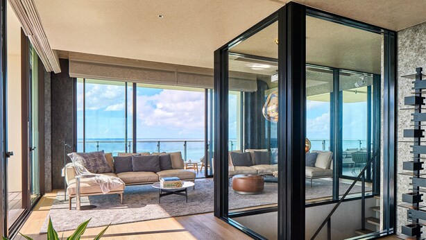 Un vaste salon doté d’une grande porte-fenêtre coulissante donnant sur un balcon avec vue sur la mer.