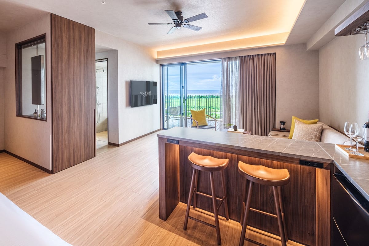 A modern kitchen with a bar area, wooden flooring, and a view of the outdoors.