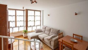 A living room with a sofa, a dining table, and a staircase.