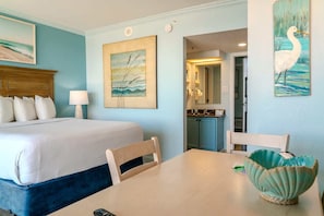 Habitación de hotel con una cama, una mesa con un bol, una silla y un cuadro en la pared.
