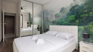 Ein Schlafzimmer mit einem großen Bett, einem Nachttisch, einem Spiegel und einem Wandbild von einem Wald.