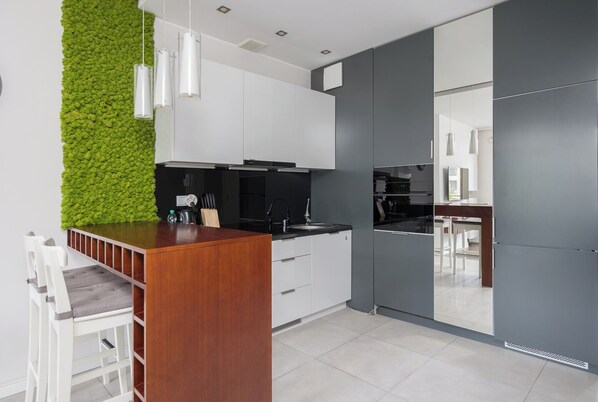 Una cocina moderna con armarios blancos, una isla de madera y un jardín vertical verde.