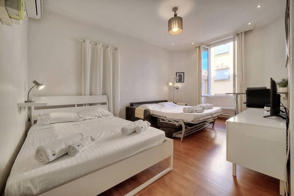 Una habitación de hotel con una cama grande, un escritorio con computadora y una ventana con cortinas.