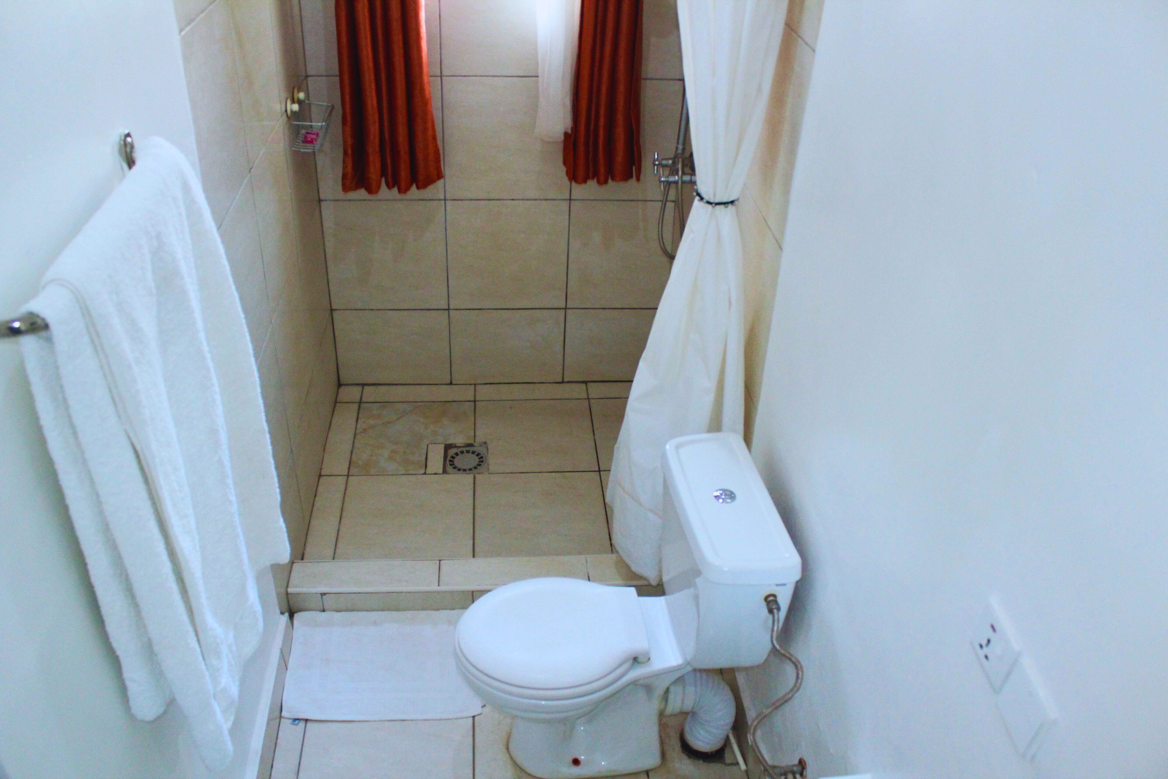 A small bathroom with a toilet, a shower, and a towel rack.