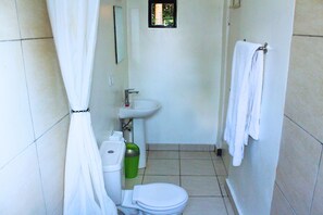 A small, clean bathroom with a toilet, sink, and shower curtain. - Salama Village Kigali (Kigali)