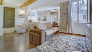 Un salon moderne avec un canapé, une table basse et un tapis. Il y a également un coin cuisine équipé de placards et d’un four à micro-ondes.