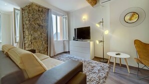 Un salon moderne avec un mur d’accent en pierre, un canapé, un téléviseur, une petite table ronde et un fauteuil.