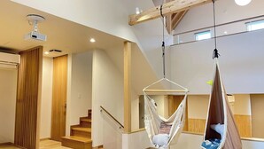 Ein modernes Interieur mit einer Holztreppe, einem Hängesessel und einem Projektor an der Decke.