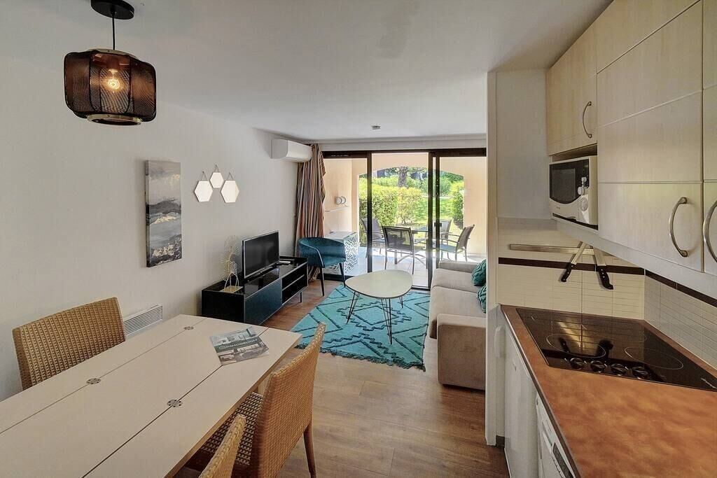 Una cucina moderna con microonde, fornello e pensili. C'è un'area pranzo con tavolo e sedie, e un soggiorno con divano e televisione.