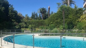 A circular pool with a metal railing, surrounded by lush greenery and trees. - Upstays Sea View Terrace 47m² Apartment (Cannes)