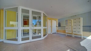 Un hall d’hôtel avec une cloison en verre, des casiers et un sol carrelé.