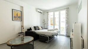Een moderne slaapkamer met een bed, een glazen tafel en een stadsgezicht poster aan de muur.