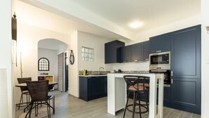 Een moderne keuken met donkerblauwe kastjes, een wit eiland en een ingebouwde magnetron.