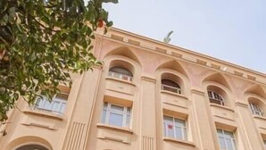 Un edificio de varios pisos con fachada color beige, que presenta una tienda con un letrero que dice 