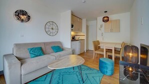 A modern living room with a sofa, coffee table, and a dining area with a table and chairs.