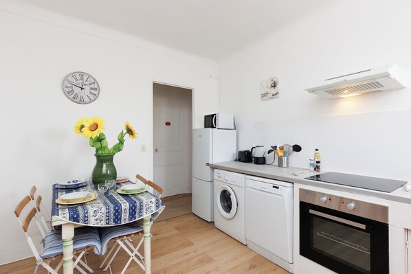 A compact kitchen with a washing machine, microwave, and oven.