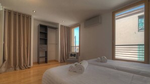 Ein Hotelzimmer mit zwei Betten, einem Schrank, einem Stuhl und einem Balkon mit Blick.