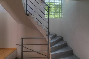 A staircase with a metal handrail and a window with a grid pattern.