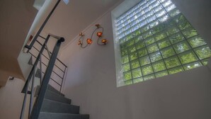 Eine Treppe mit Metallgeländer, ein Fenster mit Gittermuster und Wandleuchten.