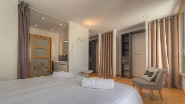 Ein Hotelzimmer mit einem großen Bett, einem Sessel, einem Schreibtisch und einem Kleiderschrank.