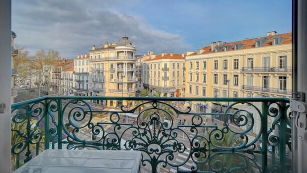 A balcony with ornate metal railings overlooking a street with multi-story buildings. - Upstays Terrace 24m² Studio Carnot (Cannes)