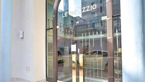 L’entrée d’un immeuble avec une porte en verre et l’inscription « LE PALAZZO ».