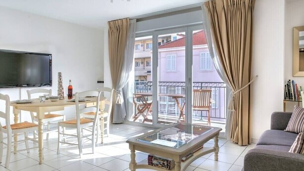 Un salon bien éclairé comprenant un coin repas, une table basse avec un plateau en verre et un canapé.