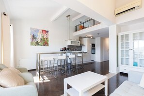 Un espacio habitable moderno con cocina, comedor y un dormitorio en entrepiso con balcón.
